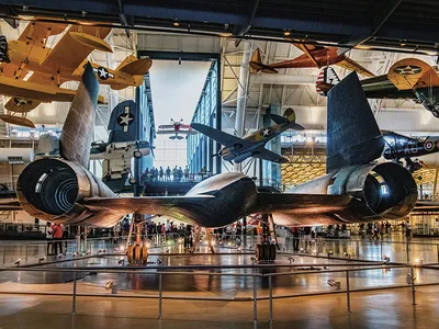 Multiple aircraft are on exhibit, including five suspended from the ceiling. Displayed on the floor is the Lockheed SR-71, viewed from the rear--the exhaust nozzles of the powerful jet engines in full view.