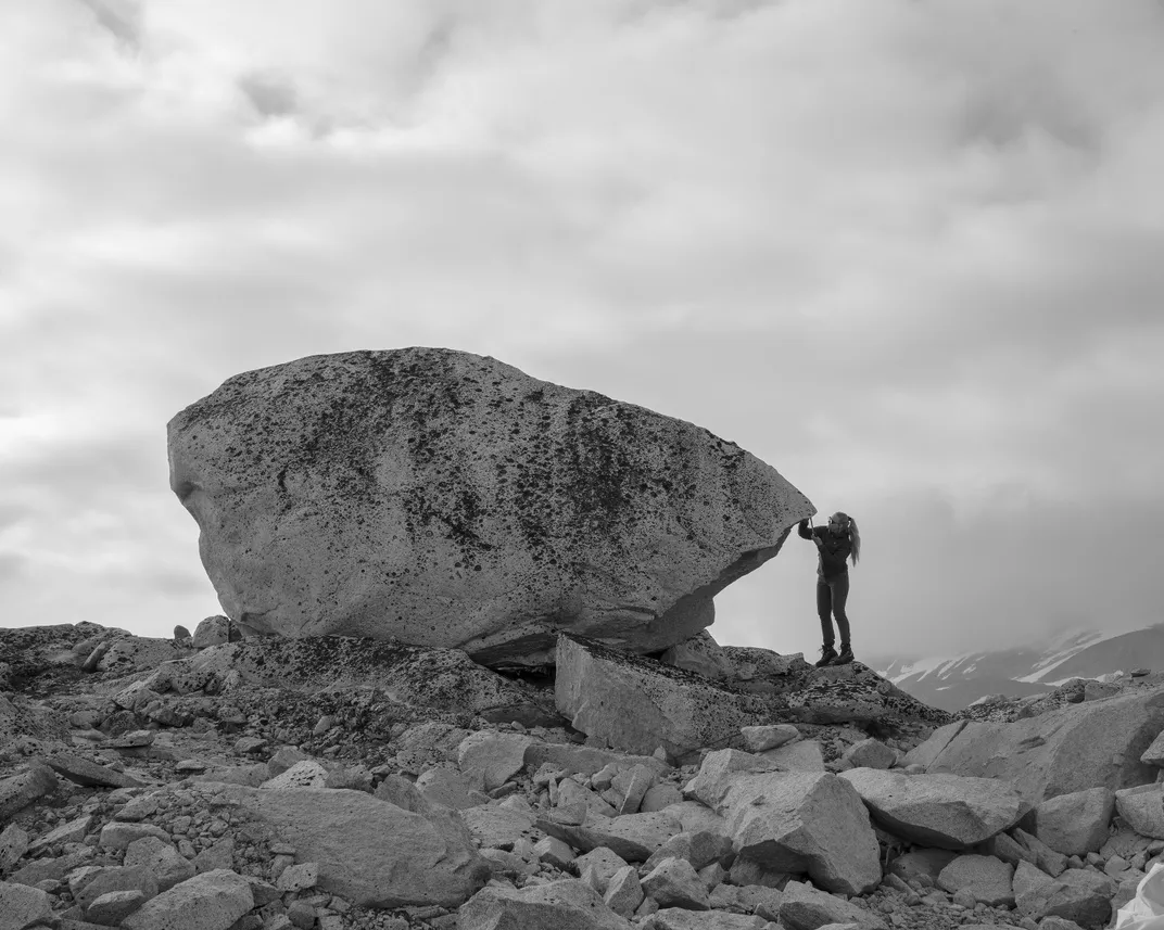 Fabienne Meier jots down data about a large boulder. Scars and shapes offer clues about how glaciers moved across the landscape in the distant past.