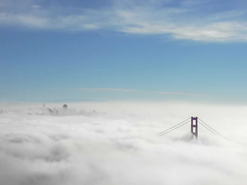 The top of the Golden Gate Bridge in San Francisco peaks out through heavy white cloud cover