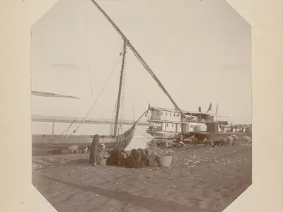 A group of women in traditional dress stand beside a Thomas Cook boat on the Nile in 1904. 